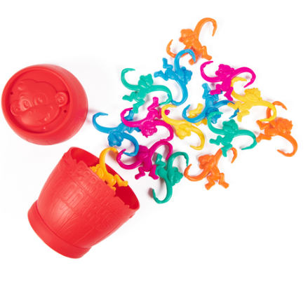 Colorful plastic monkey toys spilling out of a red container on a white background